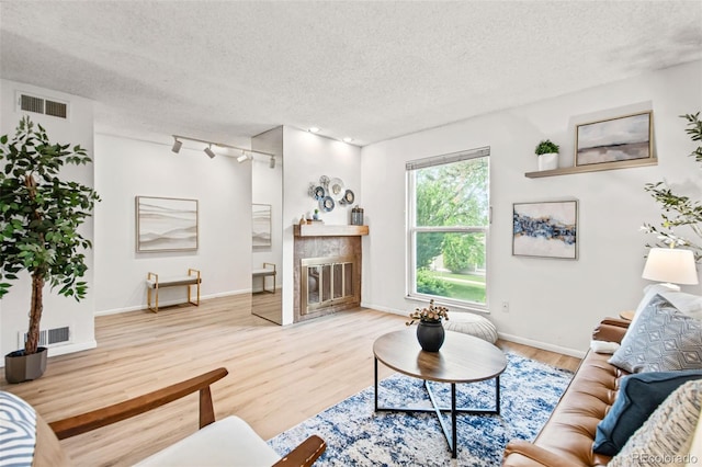 10311 E Evans Ave Unit 132, Aurora, CO 80247 - living room with a textured ceiling, wood finished floors, a tile fireplace, baseboards, and rail lighting