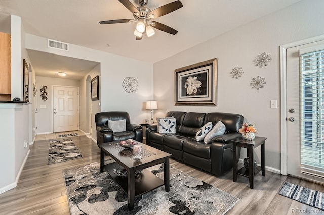 living room with visible vents, light wood-style flooring, baseboards, and ceiling fan