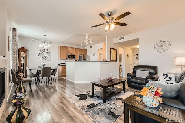 living area featuring ceiling fan, visible vents, arched walkways, and light wood-type flooring