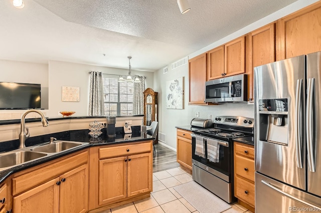 kitchen featuring dark countertops, visible vents, light tile patterned floors, stainless steel appliances, and a sink