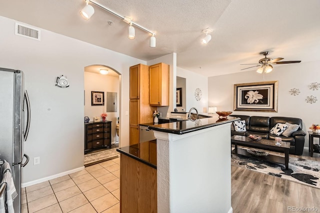 kitchen with visible vents, dark countertops, open floor plan, freestanding refrigerator, and arched walkways