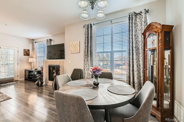 dining room with visible vents, baseboards, a chandelier, a fireplace, and wood finished floors