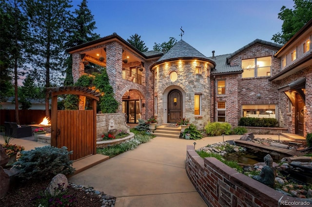 view of front of home with stone siding, a tiled roof, and brick siding