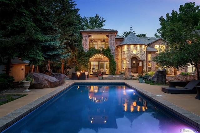 pool at dusk featuring an outdoor hangout area and a patio