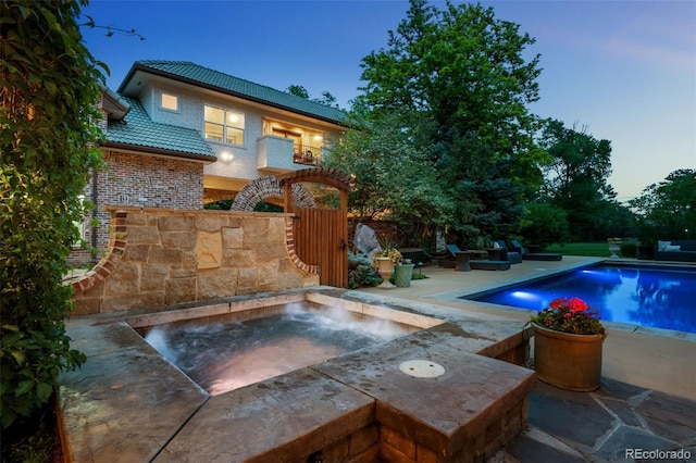 pool at dusk with a patio area