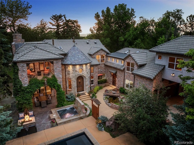 back house at dusk with a fire pit and a patio