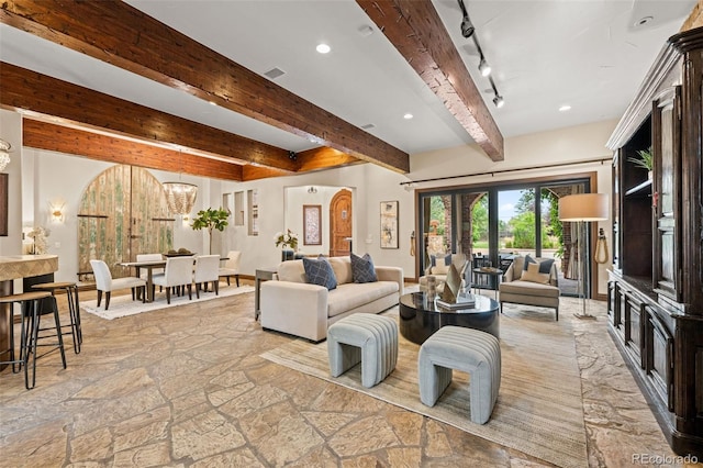 living room with a chandelier, rail lighting, and beamed ceiling