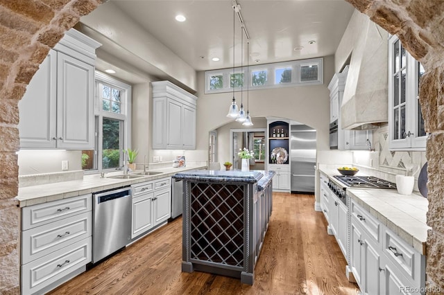 kitchen with tasteful backsplash, custom exhaust hood, sink, white cabinetry, and stainless steel appliances