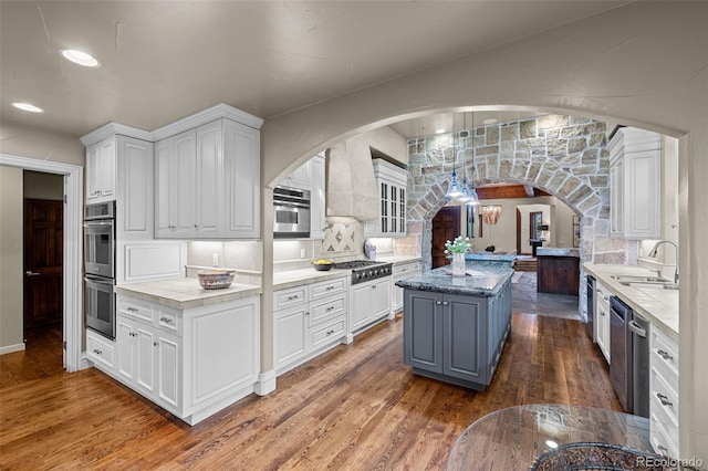 kitchen with stainless steel appliances, sink, white cabinetry, and a center island