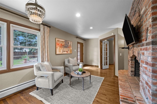 living room featuring a baseboard heating unit, a brick fireplace, dark hardwood / wood-style flooring, and a notable chandelier