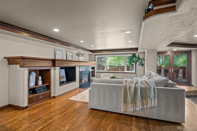 living room featuring french doors, crown molding, wood-type flooring, and a tray ceiling