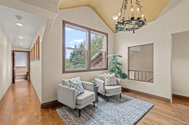 sitting room featuring light wood-type flooring, a notable chandelier, and vaulted ceiling