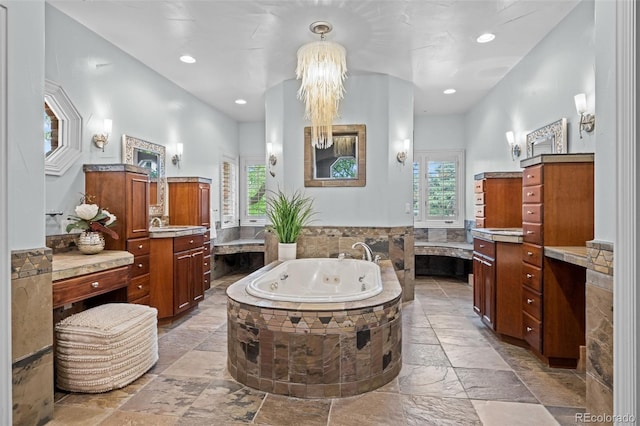 full bathroom with a healthy amount of sunlight, stone tile floors, vanity, and a whirlpool tub