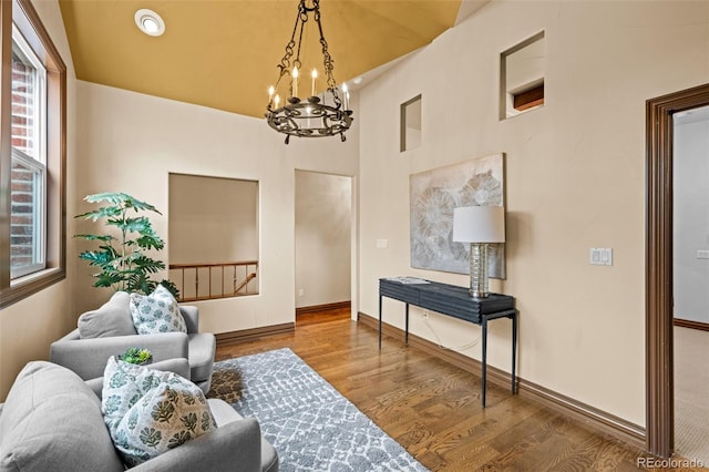 living area featuring a notable chandelier, baseboards, and wood finished floors