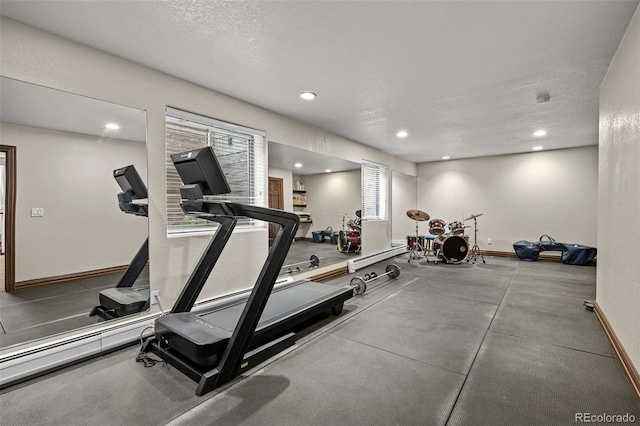 exercise room with baseboards, a textured ceiling, and recessed lighting