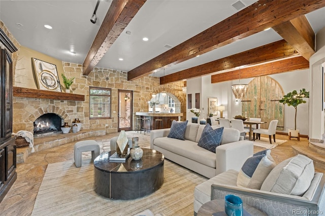 living room with stone finish floor, beamed ceiling, a fireplace, a notable chandelier, and recessed lighting