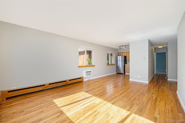1144 N Ogden St Unit 304, Denver, CO 80218 - unfurnished living room featuring a baseboard heating unit, light wood-style floors, rail lighting, and baseboards