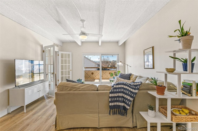 living room with beam ceiling, a textured ceiling, light hardwood / wood-style flooring, and ceiling fan