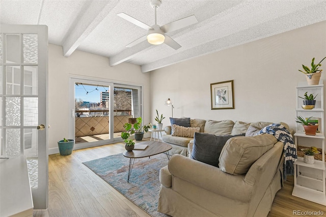 living room featuring beam ceiling, ceiling fan, hardwood / wood-style floors, and a textured ceiling