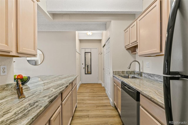 kitchen with light brown cabinets, sink, stainless steel appliances, light stone counters, and light hardwood / wood-style floors