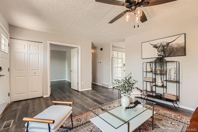 living area featuring wood finished floors, a ceiling fan, a textured ceiling, and baseboards