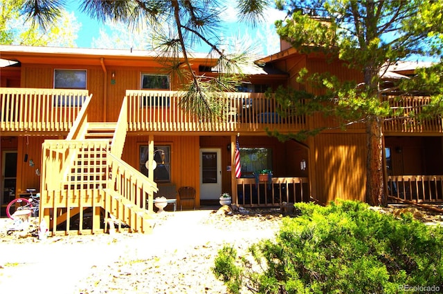 rear view of property featuring stairs and a wooden deck