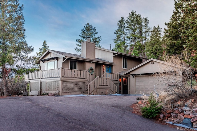 view of front of property featuring driveway, a chimney, and an attached garage