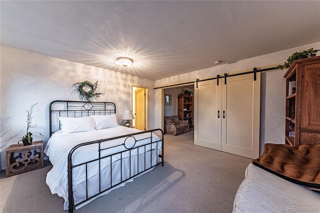 bedroom featuring carpet floors, a barn door, a textured ceiling, and a closet