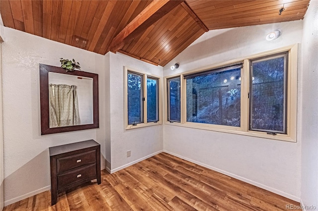 spare room featuring lofted ceiling, wooden ceiling, wood finished floors, and baseboards