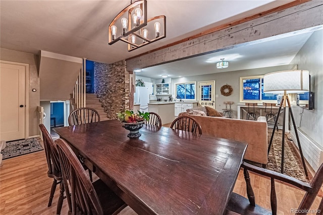 dining area featuring light wood finished floors and stairway