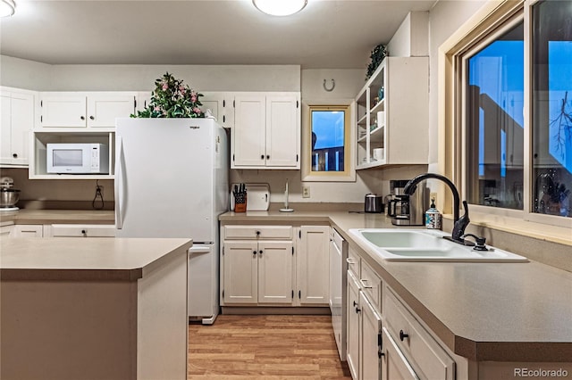 kitchen with white appliances, light wood-type flooring, a sink, and white cabinetry