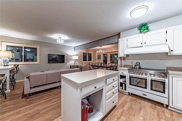 kitchen featuring range with two ovens, white cabinetry, under cabinet range hood, and light wood finished floors