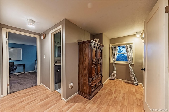 hall featuring light wood-style floors and baseboards