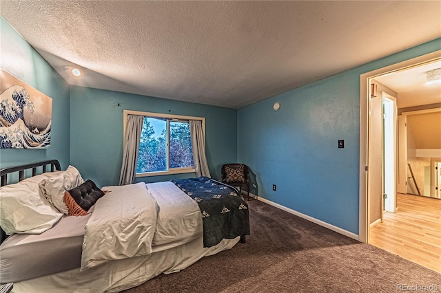 carpeted bedroom featuring a textured ceiling and baseboards