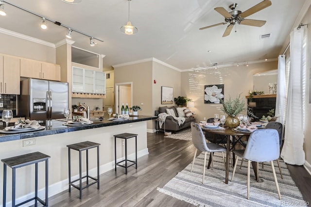 kitchen with visible vents, a kitchen bar, dark wood finished floors, stainless steel fridge, and crown molding