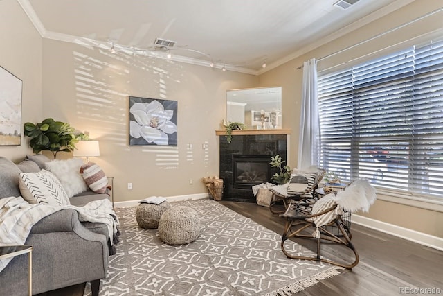 living room with visible vents, wood finished floors, ornamental molding, and a tile fireplace