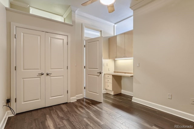 unfurnished bedroom with dark wood-style floors, built in desk, a closet, and baseboards