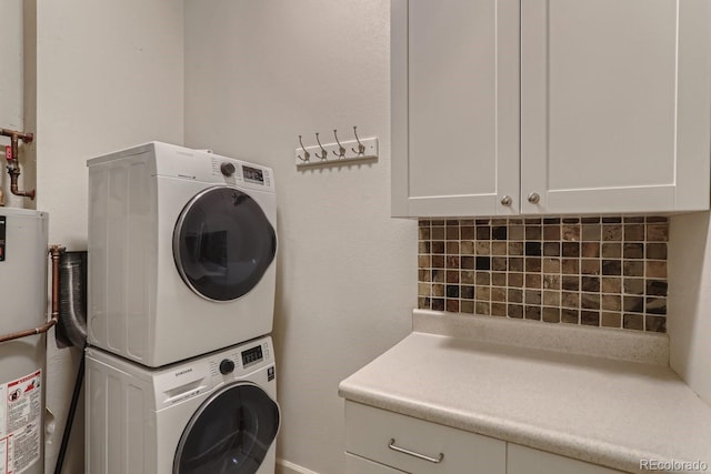 laundry area with cabinet space, gas water heater, and stacked washer / drying machine