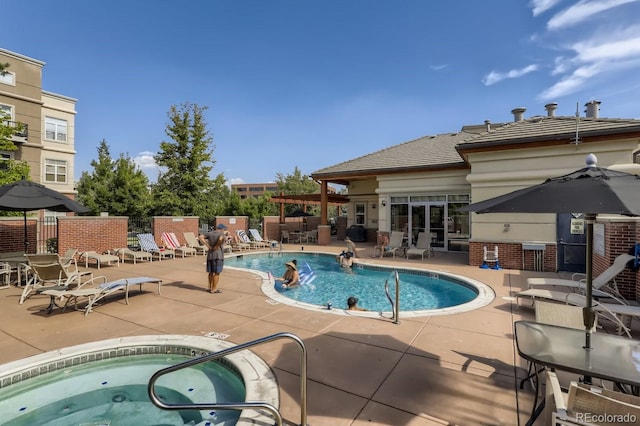 community pool featuring a community hot tub, a patio area, and fence