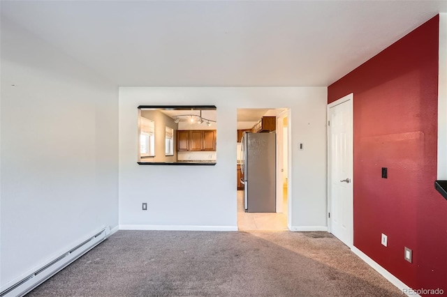 spare room featuring light colored carpet, rail lighting, and a baseboard radiator