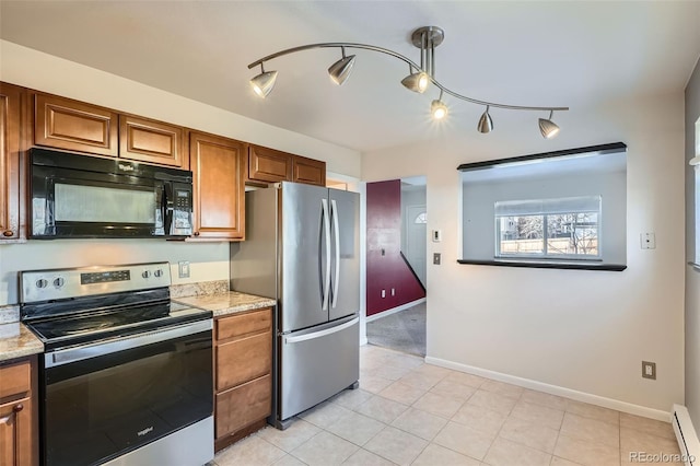 kitchen with light tile patterned flooring, light stone counters, baseboard heating, and appliances with stainless steel finishes