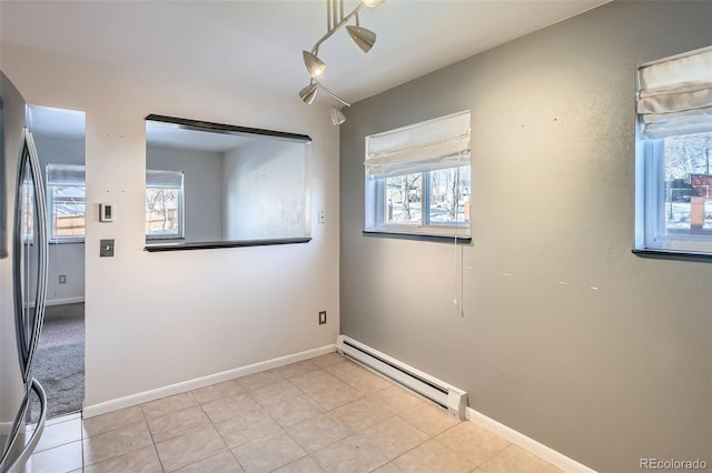 tiled spare room with a baseboard heating unit