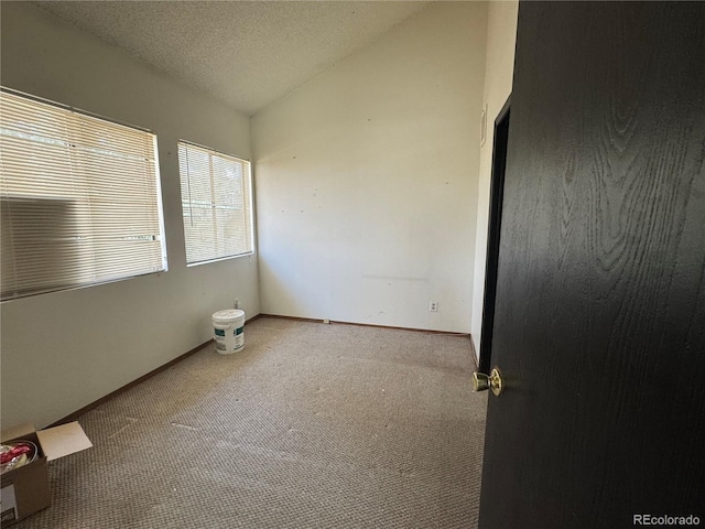 unfurnished room featuring carpet flooring, baseboards, and vaulted ceiling