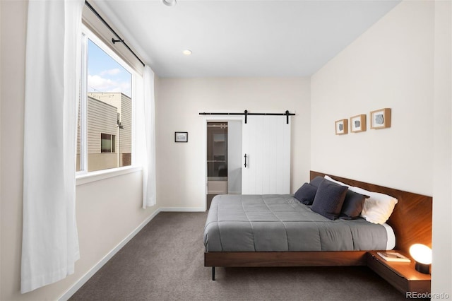 carpeted bedroom featuring a barn door and baseboards