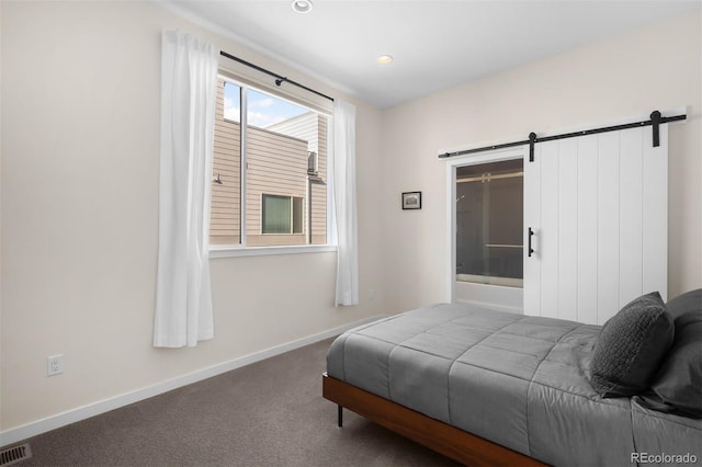 carpeted bedroom with a barn door, visible vents, and baseboards