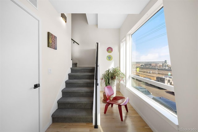 stairway featuring wood finished floors, visible vents, and baseboards