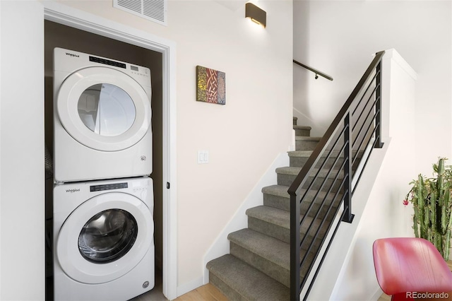 laundry area featuring baseboards, visible vents, and stacked washer / drying machine