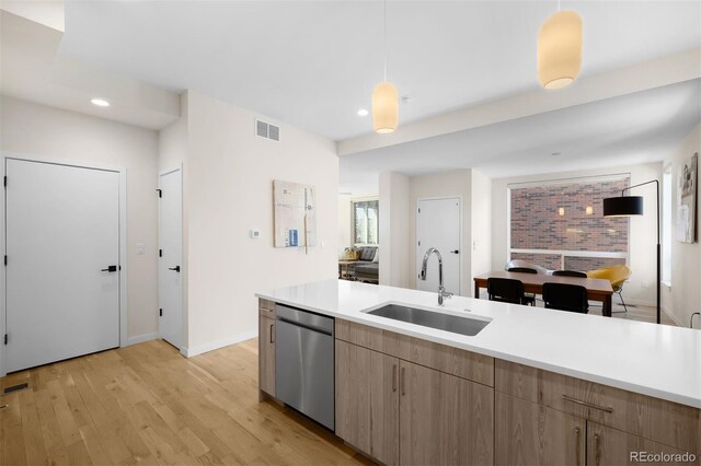 kitchen with light wood finished floors, visible vents, dishwasher, light countertops, and a sink