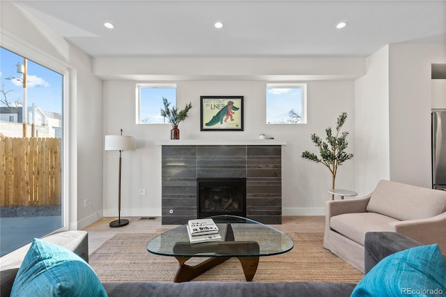 living area featuring wood finished floors, a glass covered fireplace, and recessed lighting