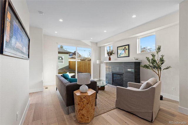 living room featuring recessed lighting, baseboards, a fireplace, and light wood finished floors